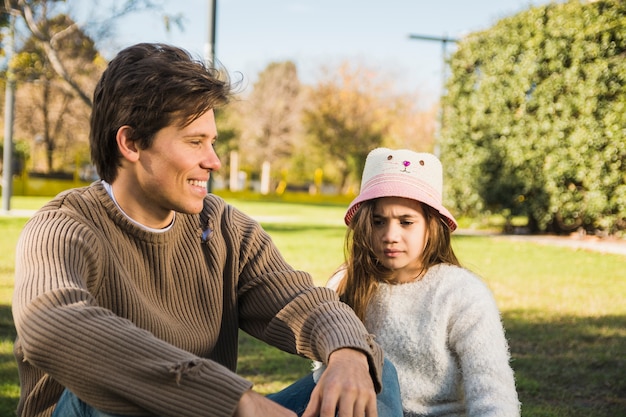 Happy father sitting in front of his daughter in park