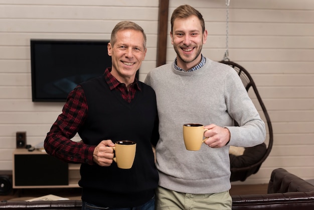 Happy father and son posing while holding cups