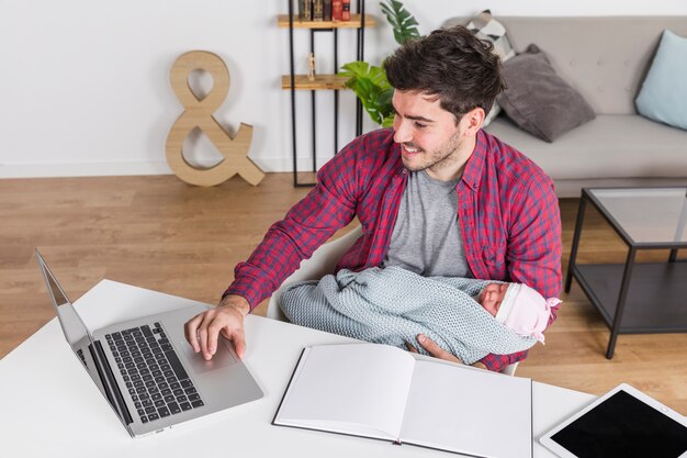 Happy father with baby using laptop at desk