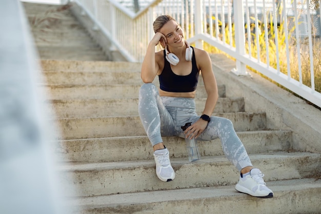 Free photo happy female athlete taking a break and relaxing on the stairs