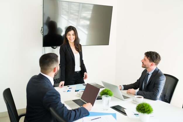 Happy female boss in a suit smiling and giving good news to her business colleagues during a work meeting