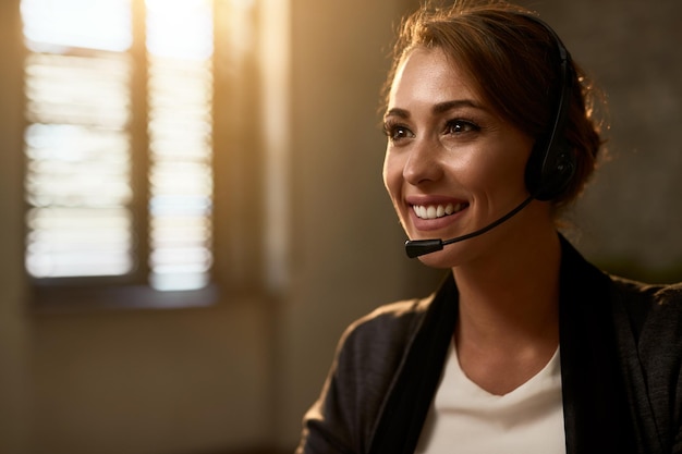 Happy female call center agent wearing headset while working in the office