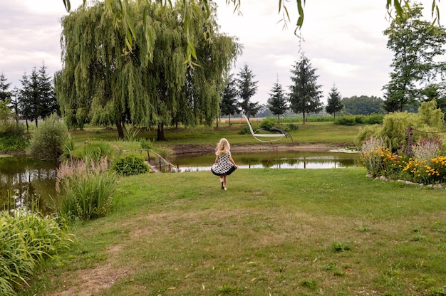 Happy female child standing in front of a pond in the beautiful garden