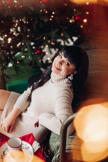 Happy female at a Christmas tree turning her smiling face to camera