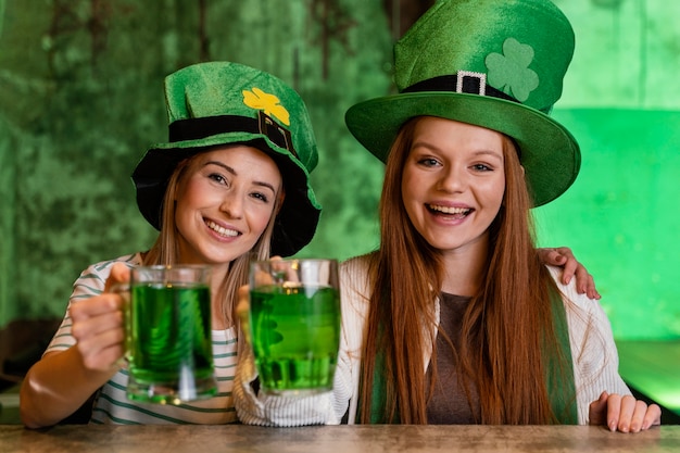 Free Photo happy female friends celebrating st. patrick's day together with drinks