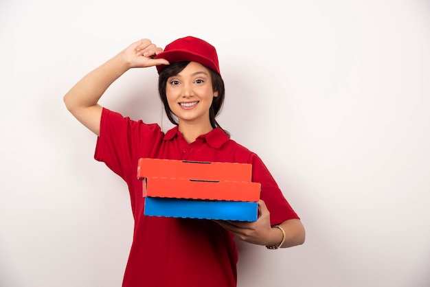 Happy female pizza delivery worker standing with three cardboards of pizza.