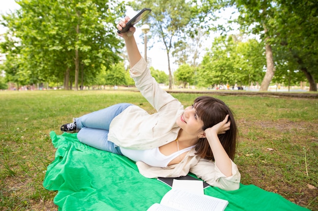 Happy female student taking selfie in park