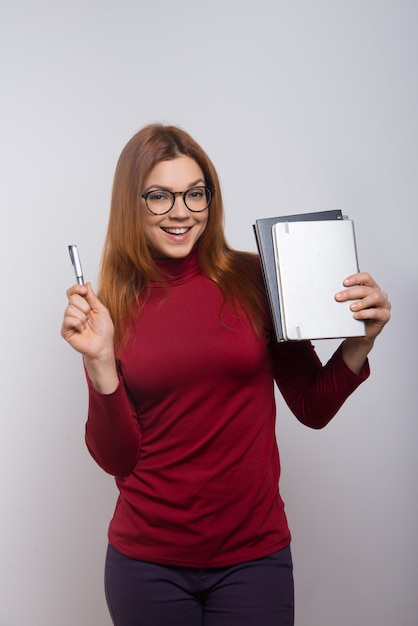 Happy female student with textbooks and pen