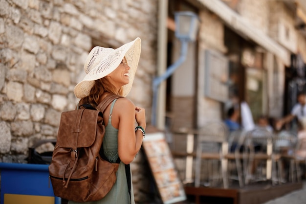 Free photo happy female tourist with back back taking a walk and exploring the town on summer vacation