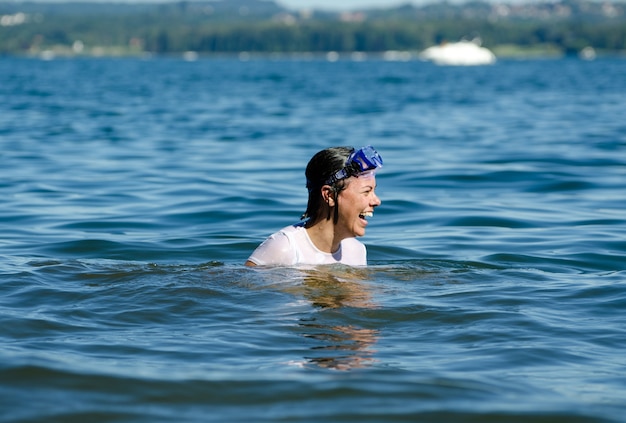 Happy female with short hair in the middle of the calm water of a lake