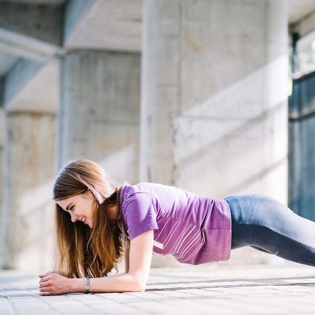 Free photo happy fitness girl with loose hair planking outdoors