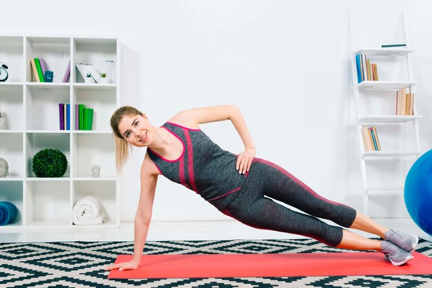 Happy fitness young woman wearing sportswear doing exercise in the living room