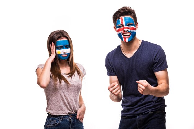 Happy Football fan of Iceland celebrate win over upset football fan of Argentina with painted face isolated on white background