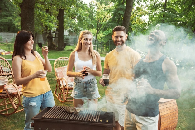 Free photo happy friends are having beer and barbecue party at sunny day