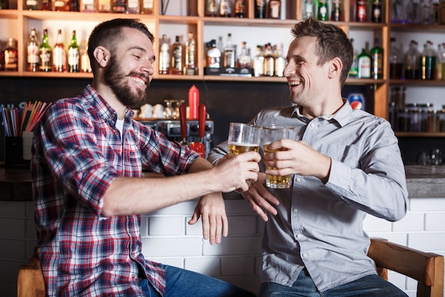 Happy friends drinking beer at counter in pub