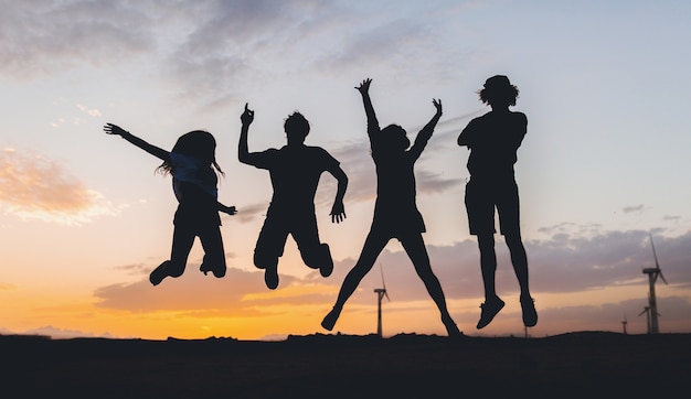 Free Photo happy friends silhouettes jumping on sunset