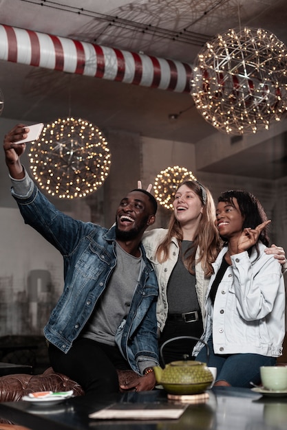 Free photo happy friends taking a selfie indoors