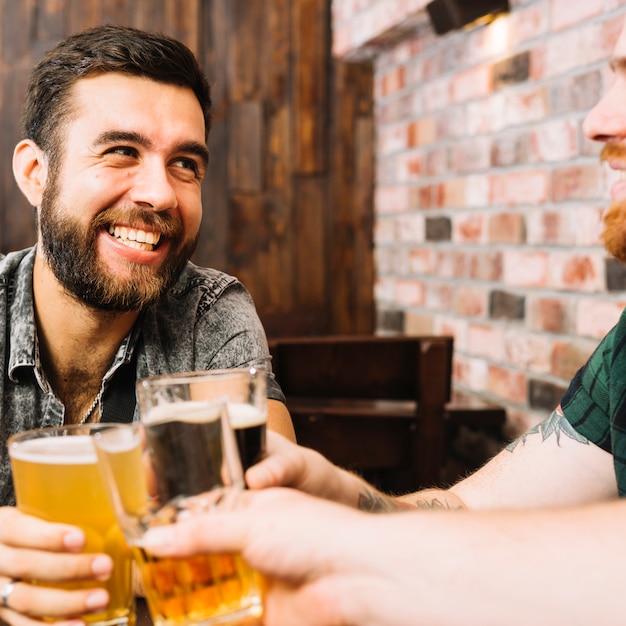 Free photo happy friends toasting glasses of alcoholic drinks in bar