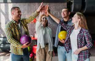 Free photo happy friends with bowling balls in a bowling club