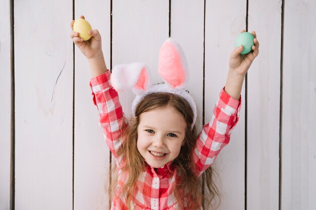 Happy girl in bunny ears with colored eggs in hands 