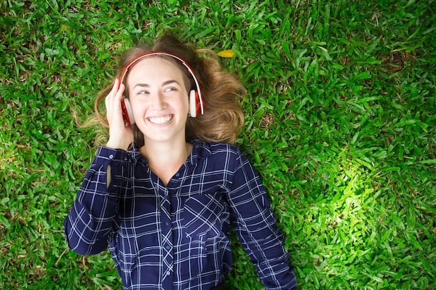 Happy Girl Enjoying Listening to Music on Grass