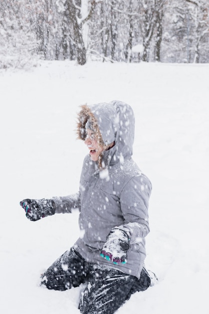 Happy girl enjoying snowfall at forest in winter