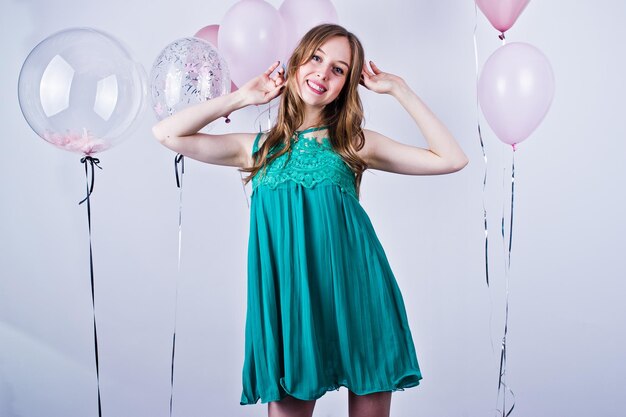 Happy girl in green turqoise dress with colored balloons isolated on white Celebrating birthday theme