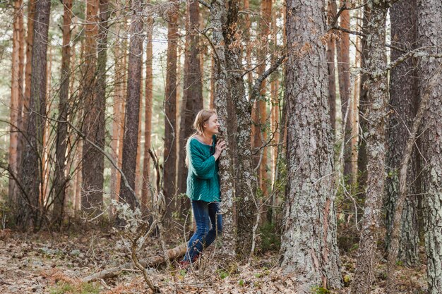 Happy girl hiding next to a tree