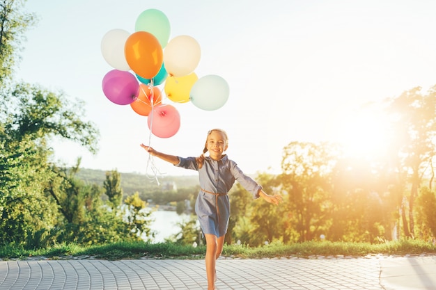 Free photo happy girl holding colorful balloons in the city park