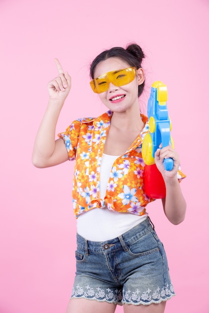 Happy girl holding a pink background water gun.