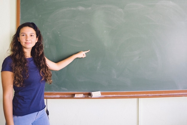 Happy girl pointing the blackboard