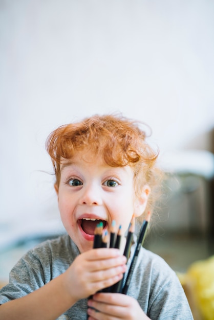 Free photo happy girl showing heap of pencils