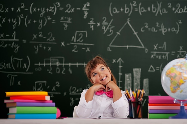 Free photo happy girl sitting and dreaming in classroom