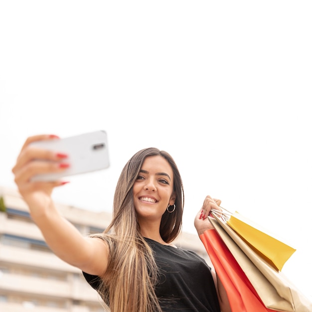 Free photo happy girl taking selfie with paper bags