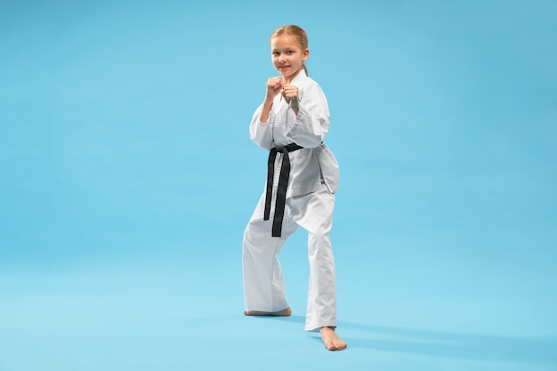 Happy girl in white kimono looking at camera while training