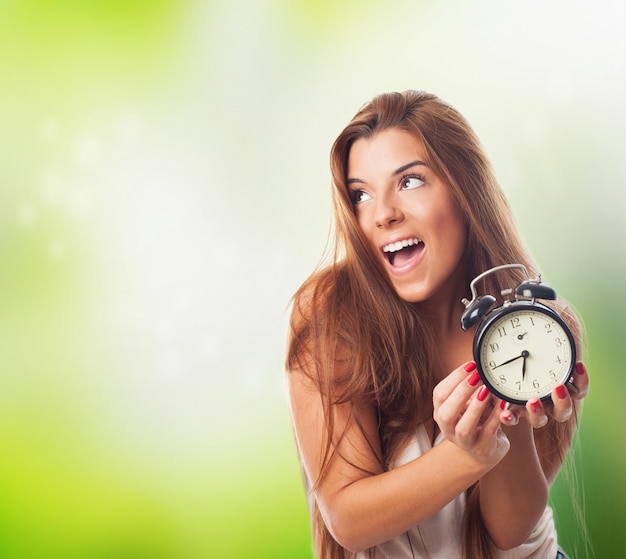 Happy girl with alarm clock in hands