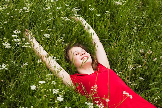 Free Photo happy girl with closed eyes lying on grass in beautiful nature