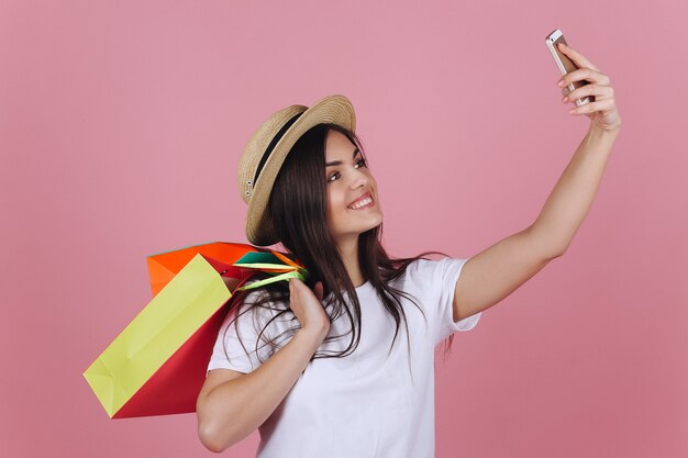 Happy girl with colorful shopping bags takes selfie on her phone