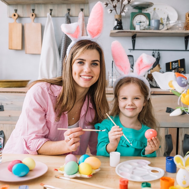 Free Photo happy girl with mother painting eggs for easter 