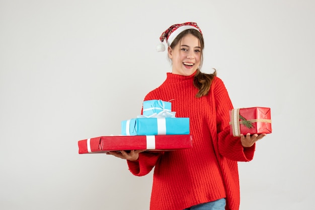 happy girl with santa hat holding her xmas gifts in both hands on white