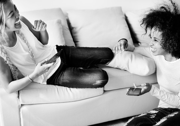 Happy girlfriends using smartphone together at home