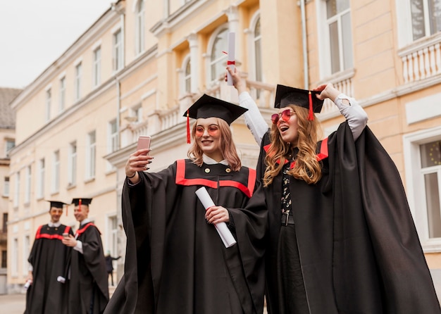 Happy girls taking selfie with diploma