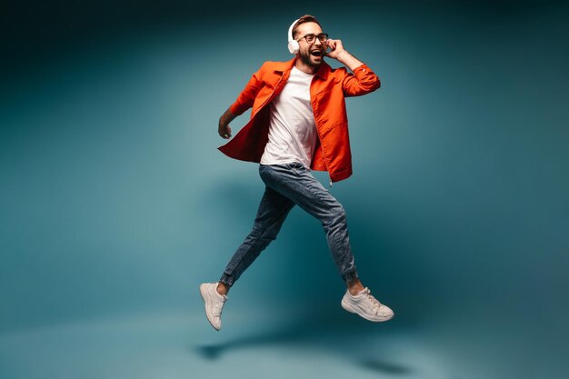 Happy guy in bright outfit listens to music in headphones