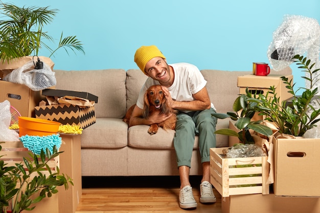 Happy guy embraces favorite dog surrounded by boxes