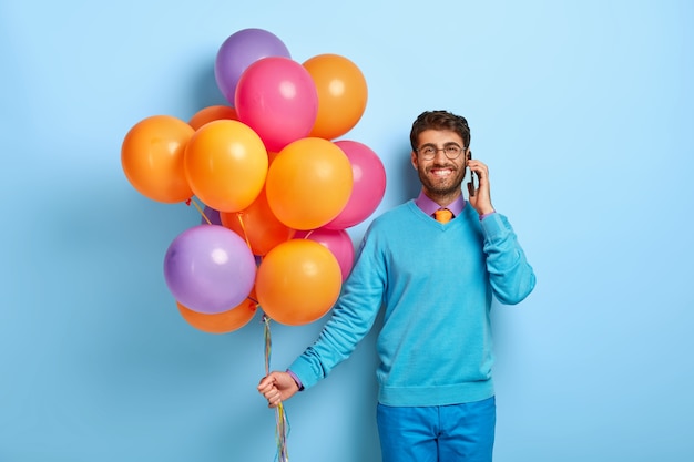 Happy guy with balloons posing in blue sweater