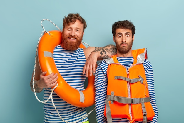 Free Photo happy guys posing at the beach with lifejacket and lifebuoy