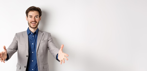 Free photo happy handsome man in suit stretch out hands to greet business partners welcome guests and smiling e