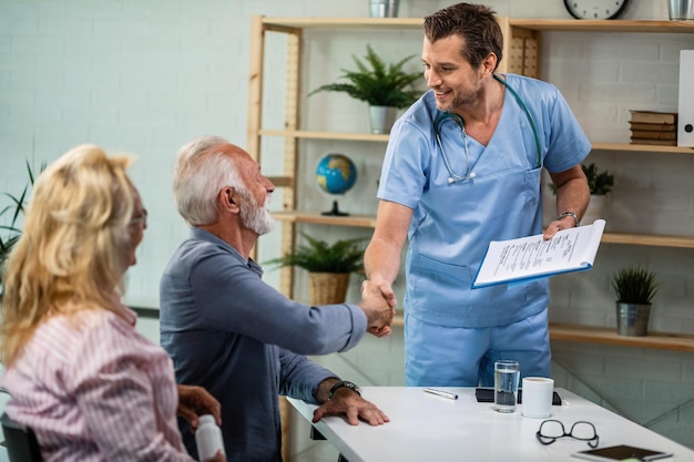 Free photo happy healthcare worker and mature couple greeting at his office men are shaking hands