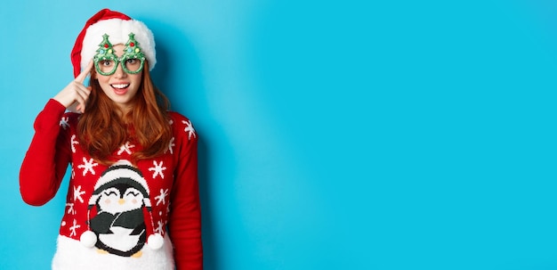 Free photo happy holidays and christmas concept funny redhead teen girl celebrating new year wearing santa hat