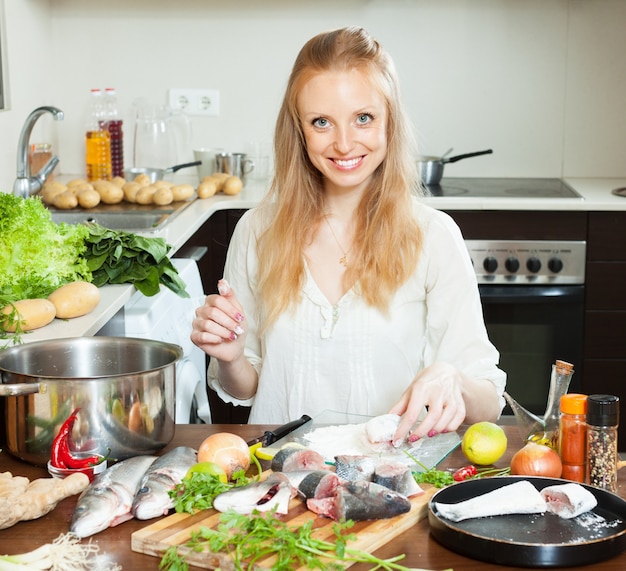 Happy housewife cooking saltwater fish in flour